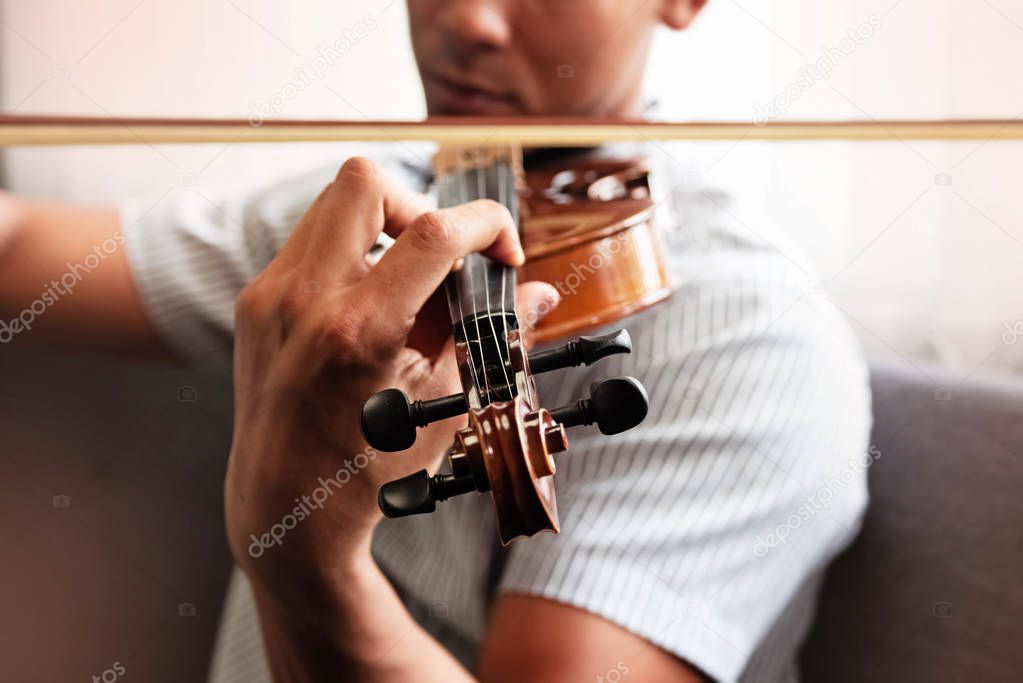 Close up human hand pressing string of violin,show how to play the instrument,blurry light around