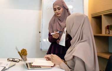 Müslüman iş kadını, ofis ve toplantı odasında birlikte evrak işi yapıyor.