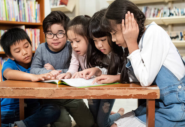 Group of children reading book togeher,with interested feeling,at library