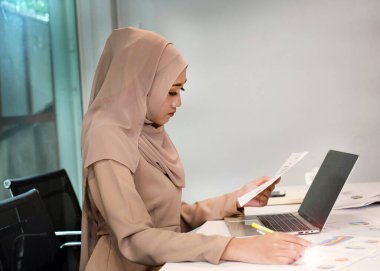 Güzel iş kadını çalışmak için dizüstü bilgisayar kullanıyor, toplantı odasında, ofis yoğun zamanında, lensler yanıp sönüyor, etrafta bulanık ışık var.