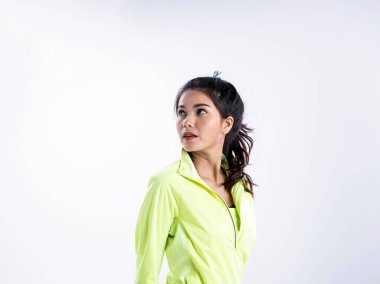 Yeşil ceket giyen güzel bayan, yüzünün sol tarafını gösteriyor, küçük bir gülümseme, arka planda poz veren, mutlu bir duygu ile