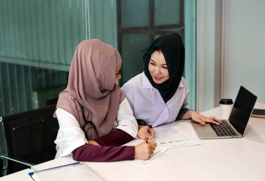 İki kadın doktor hasta tedavisi için dizüstü bilgisayar kullanıyor, yoğun zaman, hastanede çalışıyor.