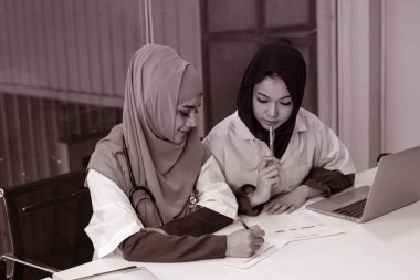 İki kadın doktor hasta tedavisi için dizüstü bilgisayar kullanıyor. Ciddi duygular, yoğun zaman, hastanede çalışma, siyah-beyaz ton, bulanık ışık.