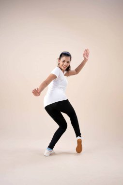 Ayakta duran güzel bir kadın ellerini havaya kaldır, biraz bükülmüş, egzersiz için dans et, mutlu hissederek.