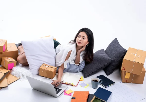 Beautiful lady laying down beside post box,using laptop and book for record data of selling online,packing for sending,work at home,e-commerce