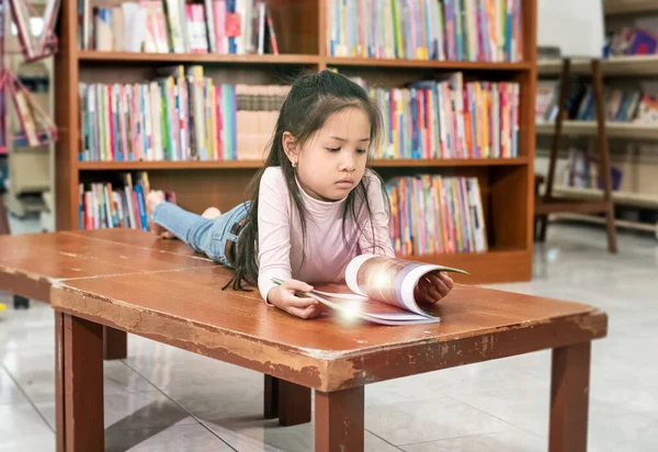 Küçük Kız Ahşap Masaya Uzanmış Kitap Okuyor Ilgili Bir Duygu — Stok fotoğraf