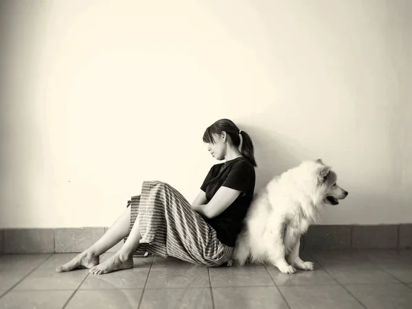 Stresli bir kadın zemin katta köpeğine yaslanır, mutsuz bir duygu, denenmiş ve sıkıcı, üzgün bir duygu. Depresif bozukluk sendromu. Klasik ton.