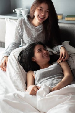 İki güzel bayan yatakta oturuyor, tatlı ve romantik duygularla, birlikte aktiviteler yapıyorlar, sabah vakti, iyi bir ilişki, en iyi oda arkadaşı..