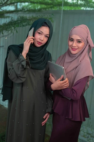 Två Vackra Muslimska Damer Pratar Mobiltelefon Och Håller Laptop Handen — Stockfoto