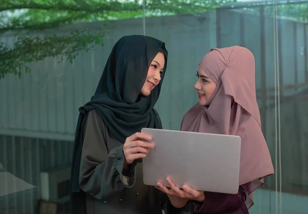 2つの美しいイスラム教徒の女性が手にノートパソコンを保持し 幸せな気持ちで笑顔成功取引後 ビジネス時間 — ストック写真