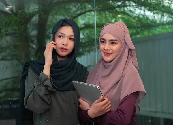 Dua Wanita Muslim Yang Cantik Berbicara Ponsel Dan Memegang Laptop — Stok Foto