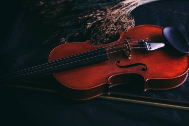 Kurumuş çiçeğin yanına konmuş ahşap keman, grunge yüzey arkaplanı, mahsul ve sanat tonu