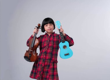 Ellerinde keman ve ukulele gösteren mutlu kız, antrenmana hazırlan.