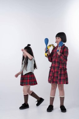 Ablası Maracas 'ı oynuyor, küçük kız kardeşi yanında dans ediyor, birlikte aktiviteler yapıyor.