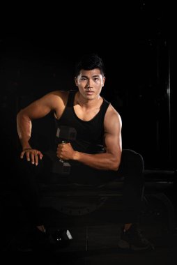 Yakışıklı adam dambıl kaldırıyor, kasları için egzersiz yapıyor, formda ve sıkı vücut, modellik yapıyor.