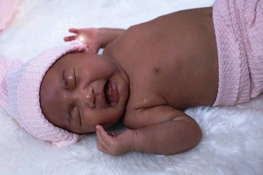 Yeni doğan bebek uzanır ve ağlar ipek kadife kumaş üzerinde, etrafında bulanık ışık, mercek efekti