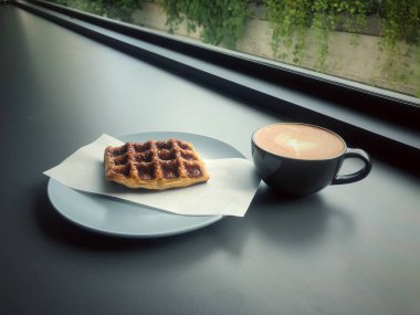 Masaya konmuş waffle ve kahve fincanı, bulanık ışık...