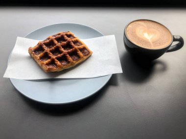 Masaya konmuş waffle ve kahve fincanı, bulanık ışık...