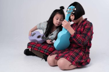 Ablam küçük kız kardeşine ukulele çalmayı öğretmeye çalışıyor.