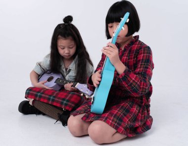 İki kız kardeş birlikte ukulele oynuyor. İlgili duygular, hobi, rahatlama zamanı.