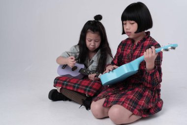 İki kız kardeş birlikte ukulele oynuyor. İlgili duygular, hobi, rahatlama zamanı.