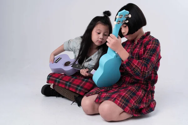 Ablam küçük kız kardeşine ukulele çalmayı öğretmeye çalışıyor.