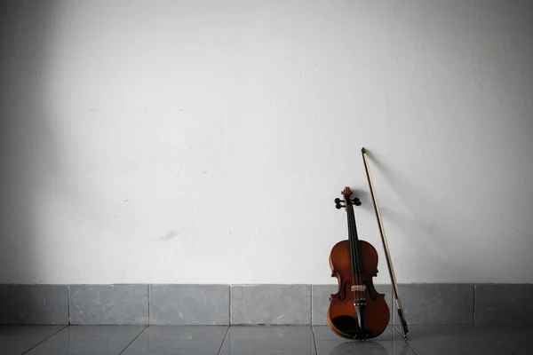 Violin and bow put on ground floor,against on the wall,blurry light around