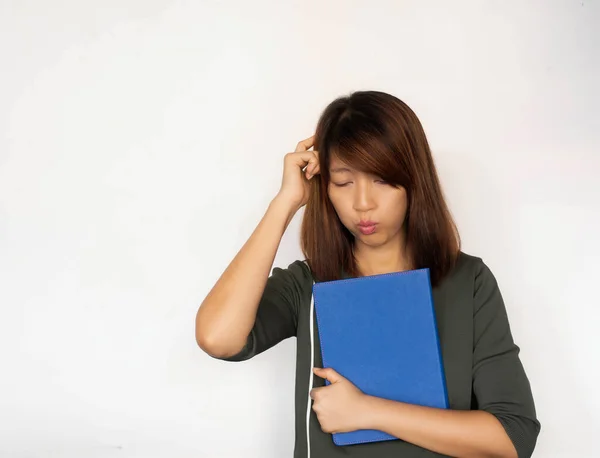 Lady hugging book in her arm,raise finger touch her head and thinking,with confuse feeling,model posing