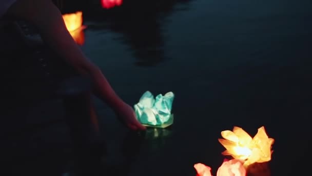 少女は水に懐中電灯を発射する。夜は水に提灯を灯す。ロマンチックな夜。美しい浮遊水のライト、ハイライトと水の反射. — ストック動画