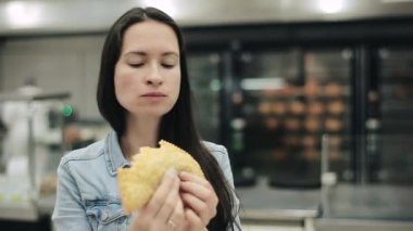 Fast food restoranında lezzetli yemekler yiyen genç bir kadın. Aç bir kadın alışveriş merkezinde sağlıksız kızarmış ve yağlı yiyecekler çiğniyor. Ucuz abur cubur yemek, kalori bağımlısı olmak.. 