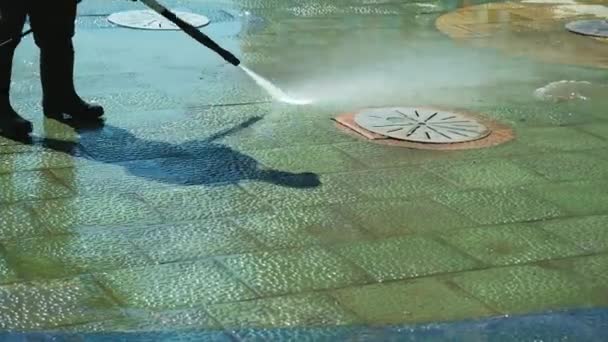 El poder de los trabajadores lava la acera cerca de la acera en el centro. Limpieza calles de la ciudad con manguera de agua. Barredora de calles limpiando asfalto. Trabajo de conserje, limpieza de calles. Concepto para empresa de limpieza . — Vídeos de Stock