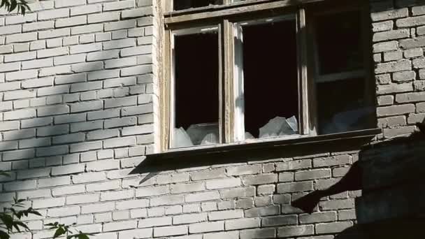 Pencere çerçevesinde kırık cam var. Terk edilmiş bir binanın cephesi. Yıkım ya da kamu malına zarar verme. Neredeyse yıkılıyor ve şehir bloğunu mahvediyordu. Vandalizm kalıbı. — Stok video