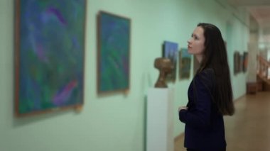 Zarif Güzel Kadın Modern Sanatlar Müzesi 'ndeki resimlere bakıyor. Şehir Sanat Galerisi 'nde Sanat Resimleri Sergisi. Fotoğraf Galerisinde Fotoğraf İzleyen Genç Kız. 