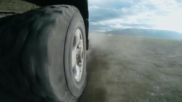 Vista de la rueda de un coche que viaja a lo largo de un valle. SUV paseos en un camino de alta montaña en un campo. Viaje en auto: fuera de la carretera viaje en la montaña. Concepto de viaje coche . — Vídeo de stock