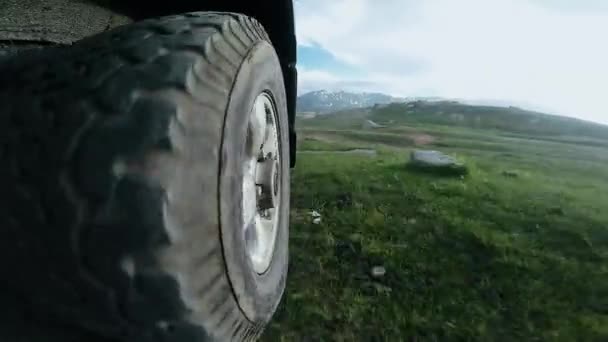 SUV monta em uma estrada de montanha alta em um campo. Vista da roda de um carro viajando ao longo de um vale. Viagem automática: off the road travel on mountain. Conceito de viagem de carro. — Vídeo de Stock