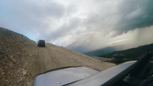 Prowadź samochód pod górę na wysokiej drodze górskiej w pochmurny dzień. Auto podróż: POV - Punkt widzenia SUV jeździ doliną z górami na wsi. Podróże off road. Koncepcja podróży samochodem. — Wideo stockowe