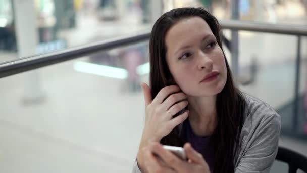 Chica pensativa utiliza un teléfono inteligente, escribe un mensaje, charlando. Mujer ansiosa buscando información en el teléfono y triste sentado en un café solo — Vídeo de stock