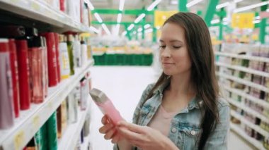 Süpermarkette kozmetik ürünlerine bakan güzel bir kadın. Ev hanımı kozmetik ürünleri marketten alıyor. Reklam işi, tüketim, güzellik kavramı