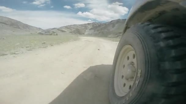 Vue de la roue d'une voiture parcourant une vallée. SUV monte sur une route de haute montagne dans une campagne. Voyage en auto : hors route voyage en montagne. Concept de voyage voiture . — Video