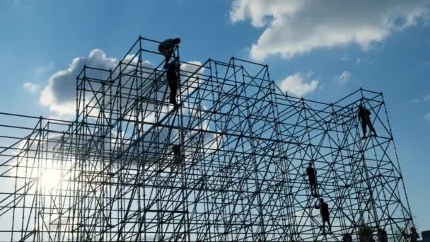 Siluetas de los hombres ingeniero trabajador en el sitio de construcción. Los trabajadores de los constructores del atardecer ensamblan el diseño. Silueta de construcción conceptual. Plan de trabajo de ingeniería. Equipo de construcción. Color azul cielo . — Vídeos de Stock