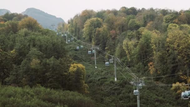 ケーブルカーは夏に豪華な山のリゾート地で観光客を持ち上げます。夏の岩のためのケーブルカーのワイドショット。山頂にあるスキーチェアリフトステーション — ストック動画