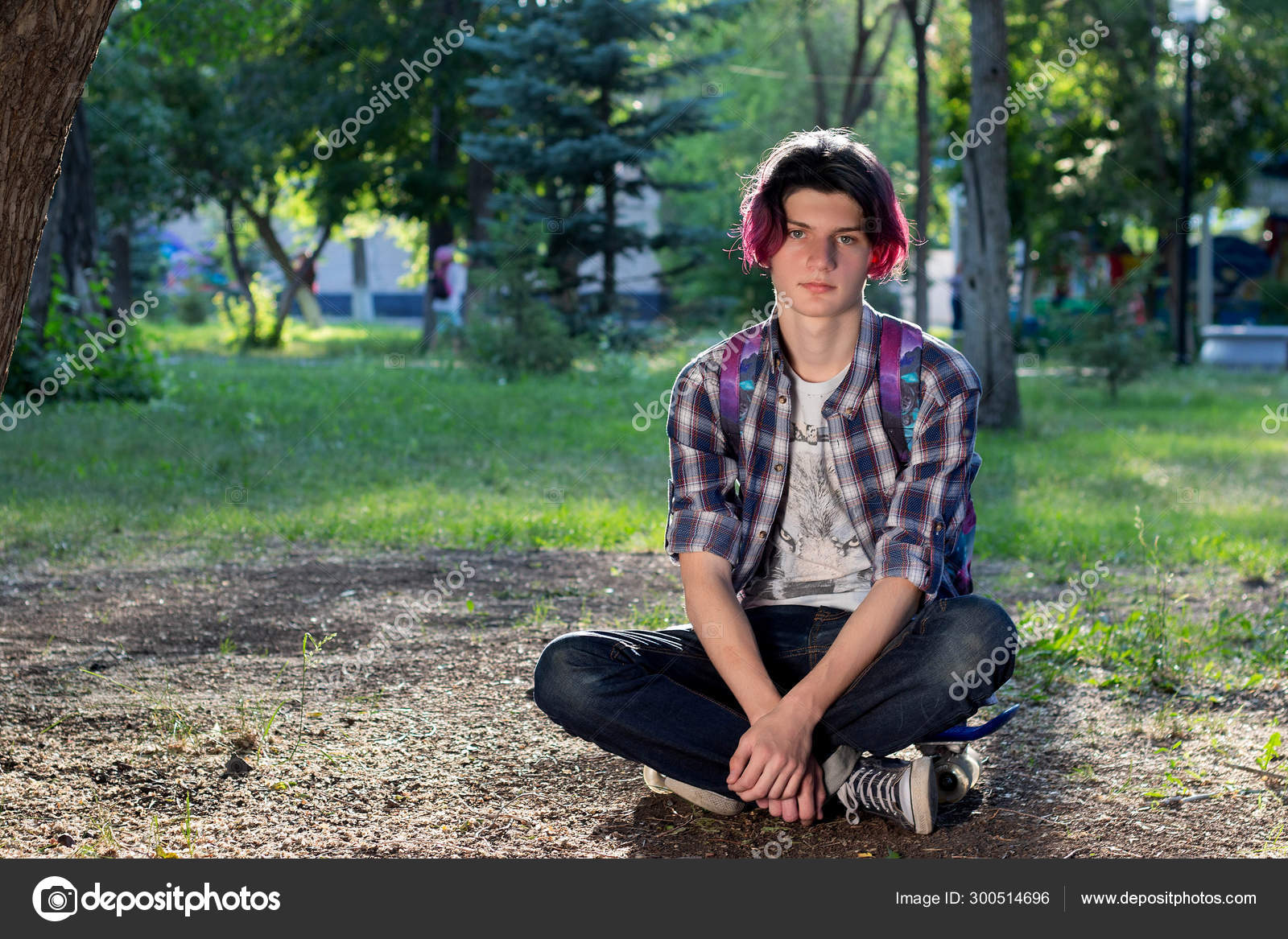 Young Guy With Purple Hair Sitting On A Skateboard In The Park