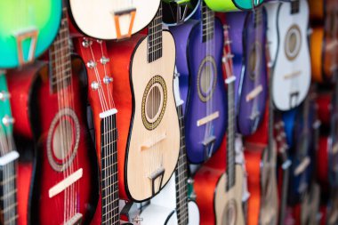 Satır bir sokak satıcısı duvarında asılı çocuklar için renkli pratik gitar.