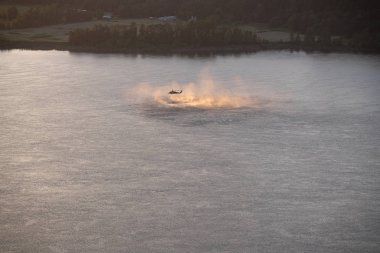 Kadar yakın çekim helikopterin eğitim kurtarma operasyonu Columbia Nehri üzerinde günbatımında. Su sıçramalarına, buharı ve spreyler nehir yüzeyden ayağa kalkın. Helikopterden ip asılı.