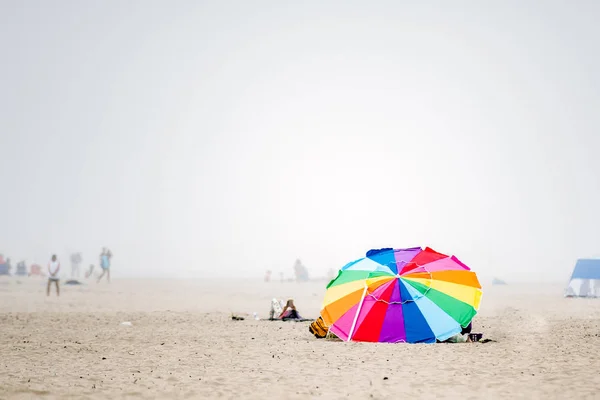 Colorful rainbow beach tent on the Seaside, oregon shore during heavy fog.
