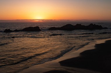 Gün batımında Oregon sahil görünümü. Güneş ufukta arka planda görünür zor. Siluetleri okyanustan yapıştırma taş. Tatil ve dinlenme için mükemmel bir kaçış yeri.