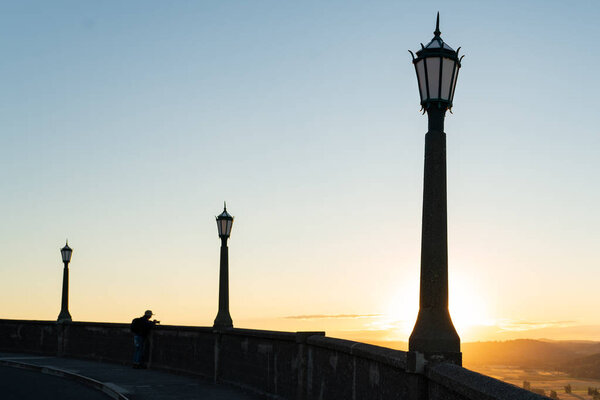 Ряд силуэтов светильника, идущих в горизонт во время заката
