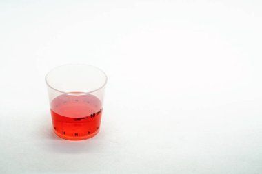 Ölçüm fincan beyaz arka plan üzerinde izole kırmızı Anti-ateş ilaç ile 10ml.