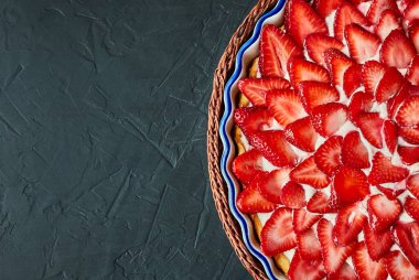 Çilekli turta mavi, hasır tepsi gri çimento arka plan, üst manzara. Boşluğu kopyala