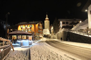 Lech, Avusturya - 04 01 2018: Kış gecesi merkezi Lech, Avusturya kayak tatil köyü Kilisesi ile